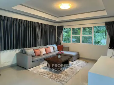 Spacious living room with modern decor and large windows offering lush garden views.