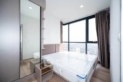Modern bedroom with large windows offering stunning city views and ample natural light.