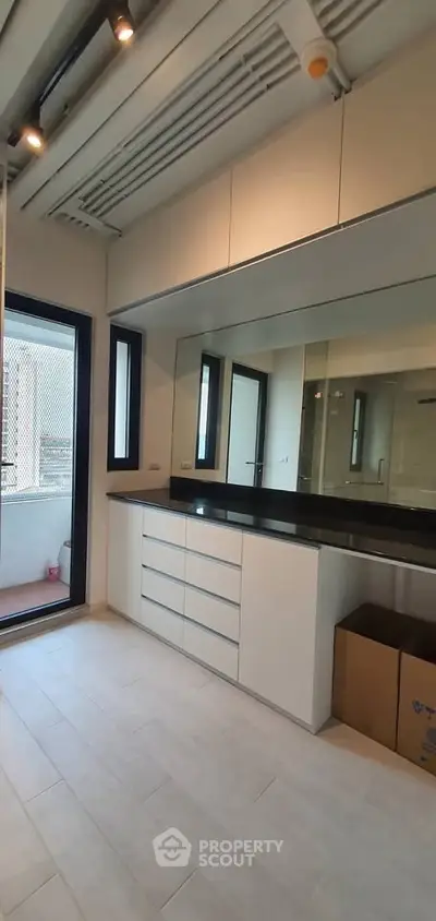 Modern bathroom with sleek cabinetry and large mirror, featuring a balcony view.
