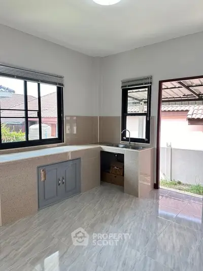 Spacious kitchen with modern countertops and large windows in a bright home.