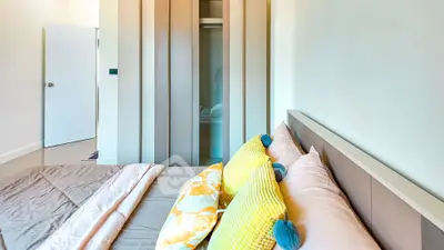 Modern bedroom with stylish decor and vibrant pillows, showcasing a sleek wardrobe and inviting ambiance.