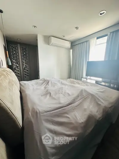 Cozy bedroom with modern decor, featuring a large bed, air conditioning, and a flat-screen TV.