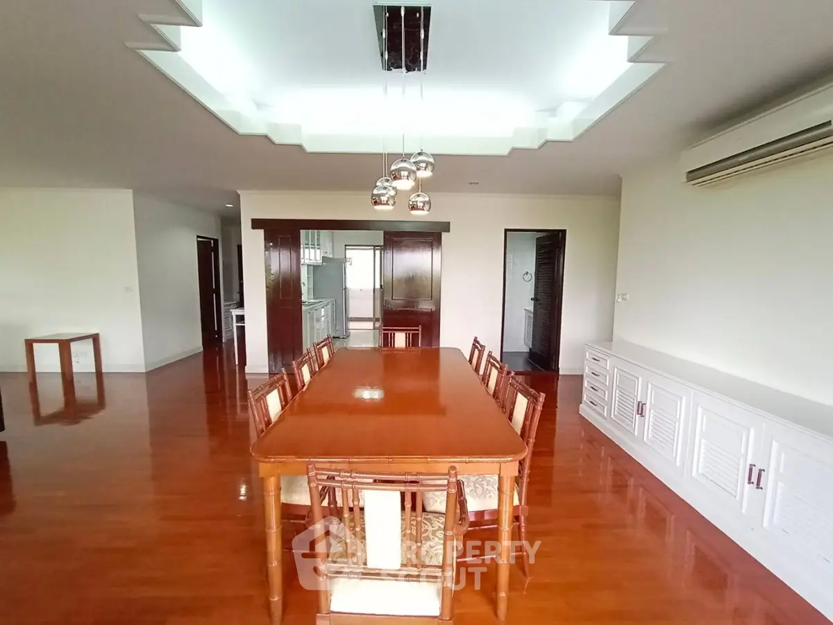 Spacious dining area with elegant wooden flooring and modern lighting in a luxurious apartment.