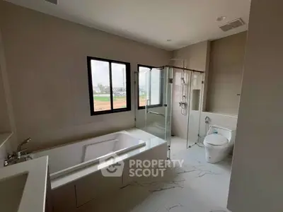 Spacious modern bathroom with bathtub and glass shower enclosure