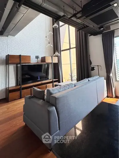 Modern living room with high ceilings, stylish furniture, and large windows offering natural light.