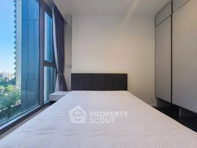 Modern bedroom with large window and built-in wardrobe in a high-rise apartment.