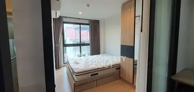 Cozy bedroom with large window and modern furnishings in a stylish apartment.