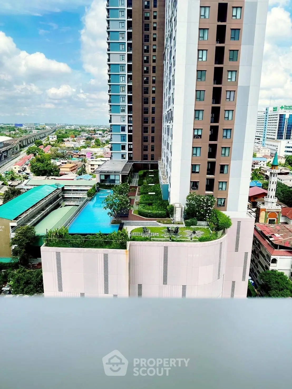 Stunning high-rise building with rooftop pool and lush garden offering panoramic city views.