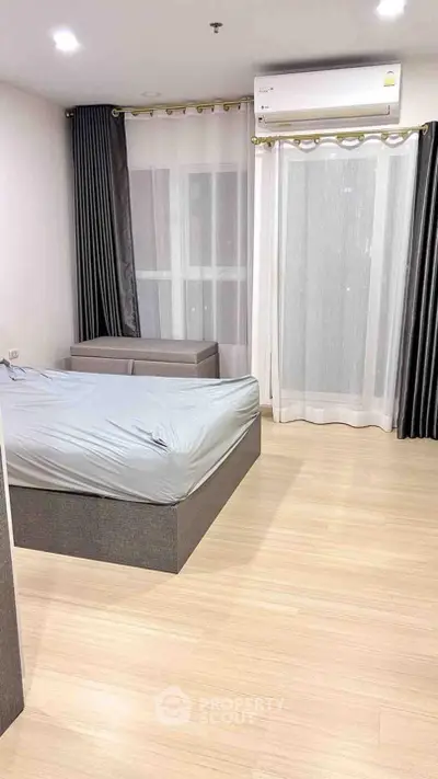 Modern bedroom with sleek design and natural light, featuring a stylish bed and elegant curtains.