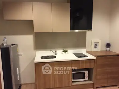 Modern compact kitchen with sleek cabinetry and built-in appliances in a cozy apartment.