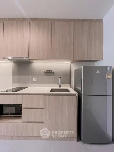 Modern kitchen with sleek cabinetry and stainless steel fridge in a contemporary apartment.