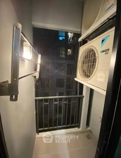 Compact balcony with air conditioning unit in modern apartment building.