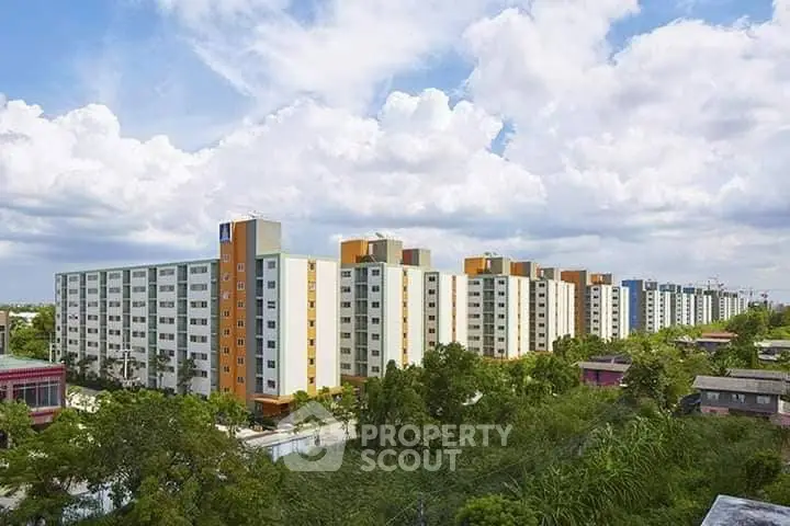 Modern apartment complex with colorful facades and lush greenery under a vibrant sky.