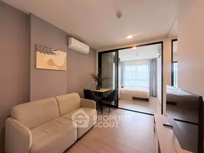 Modern living room with cozy sofa and stylish decor leading to a bright bedroom with large windows.