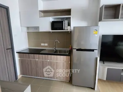 Modern kitchen with sleek cabinetry, stainless steel fridge, and built-in microwave in a stylish apartment.