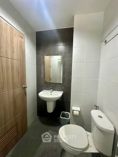 Modern bathroom with sleek fixtures and neutral tiles, featuring a wall-mounted sink and toilet.