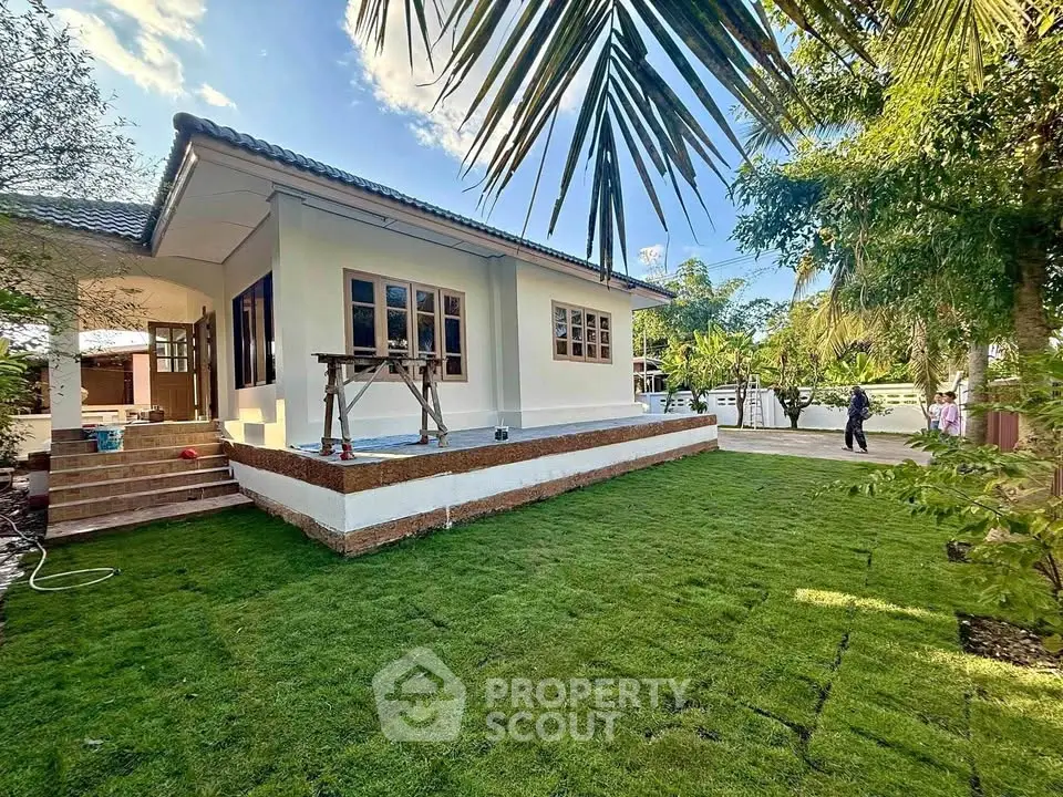 Charming single-story home with lush green lawn and tropical landscaping.