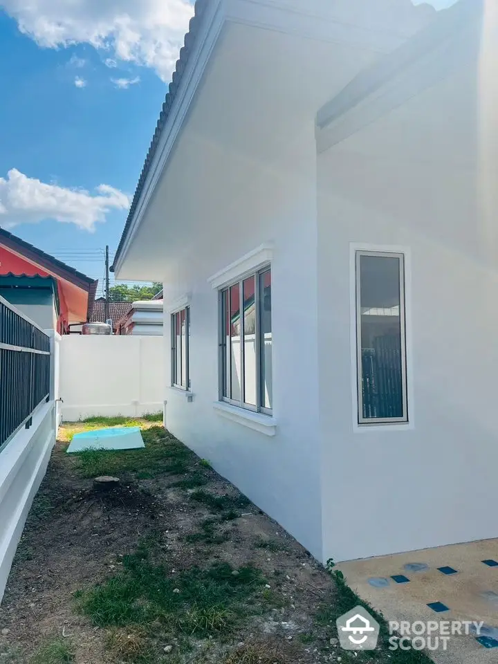 Bright and airy newly painted single-story home with spacious side yard and clear blue skies, perfect for outdoor activities and gardening.