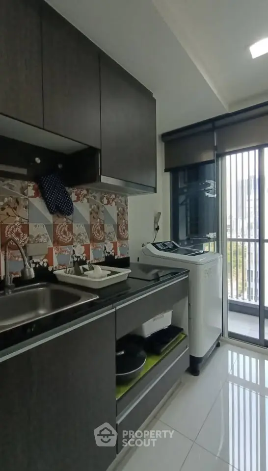 Modern kitchen with sleek cabinets and washing machine, featuring a stylish backsplash and ample natural light.