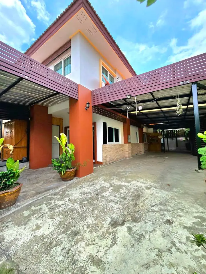 Charming two-story house with spacious carport and lush greenery, perfect for family living.
