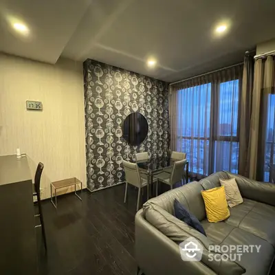 Chic modern living room with stylish dark hardwood floors, elegant patterned accent wall, and plush grey sectional sofa, perfect for urban living.