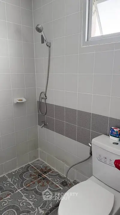 Modern bathroom with shower and toilet, featuring stylish tile design.