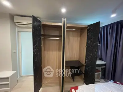 Modern bedroom with open wardrobe and air conditioning, featuring sleek design and ample storage space.