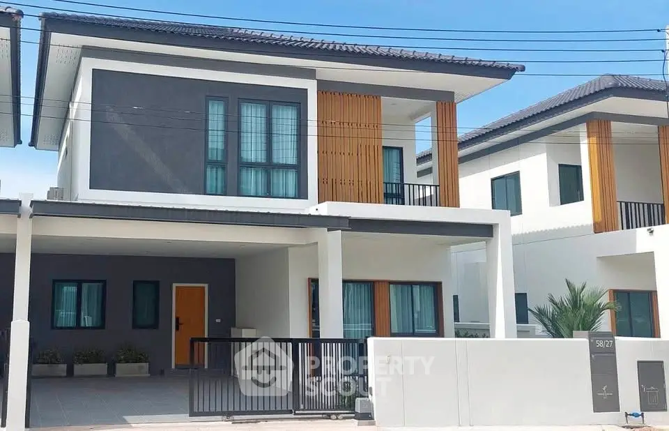 Modern two-story house with sleek design and spacious driveway in a suburban neighborhood.