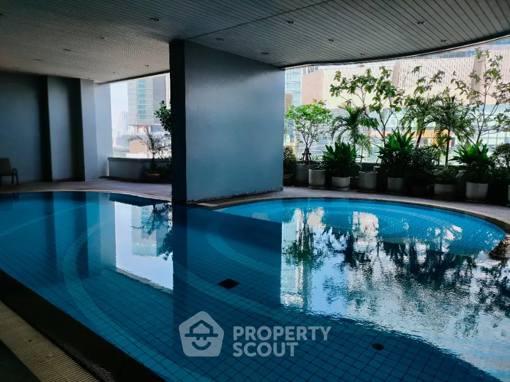 Luxurious indoor pool with city view and lush greenery, perfect for relaxation and leisure.