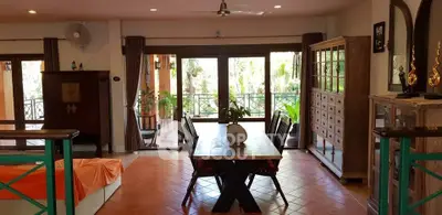 Spacious living room with dining area and garden view, featuring elegant wooden furniture.