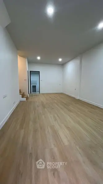 Spacious empty room with wooden flooring and recessed lighting, ideal for customization.