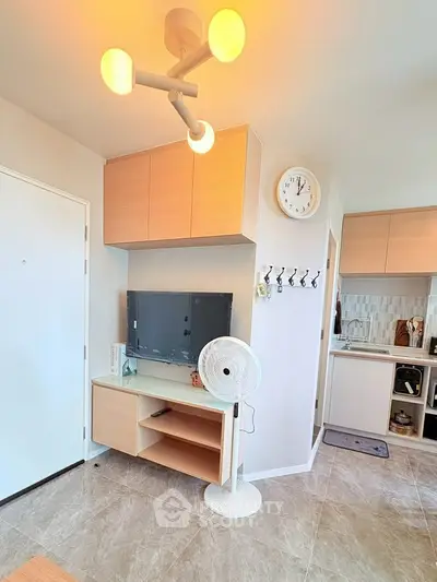 Modern living room with stylish lighting and compact kitchen area, perfect for urban living.