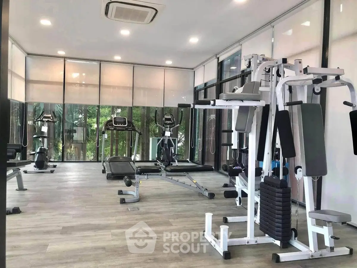Modern gym with state-of-the-art equipment and large windows offering a serene view.