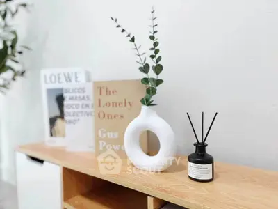 Stylish interior decor with modern vase and books on wooden shelf, perfect for contemporary living spaces.