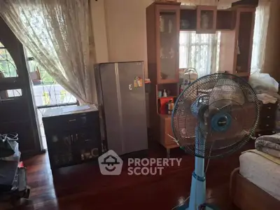 Cozy bedroom with wooden flooring and natural light, featuring a fan and storage cabinets.