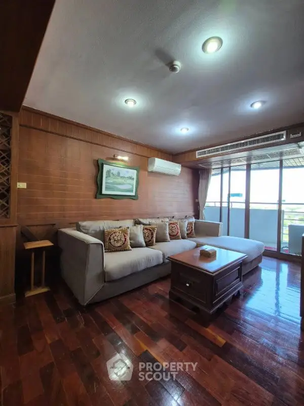 Spacious living room with cozy sofa and wooden flooring, featuring large windows for natural light.