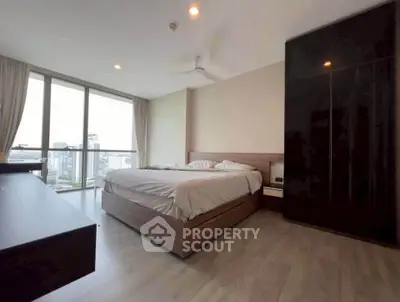 Spacious bedroom with city view and modern furnishings in high-rise apartment.
