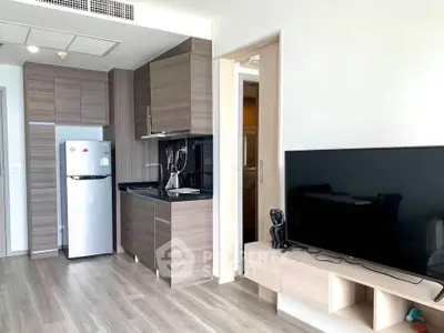 Modern apartment interior with sleek kitchen and cozy living area featuring a flat-screen TV.
