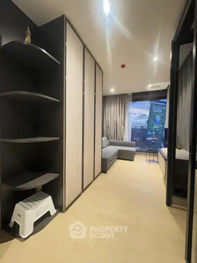 Modern living room with sleek design and city view, featuring a cozy sofa and stylish shelving.