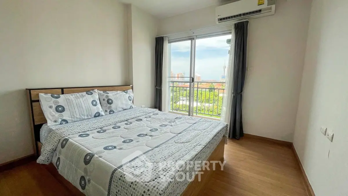 Bright bedroom with balcony and city view, featuring modern decor and air conditioning.