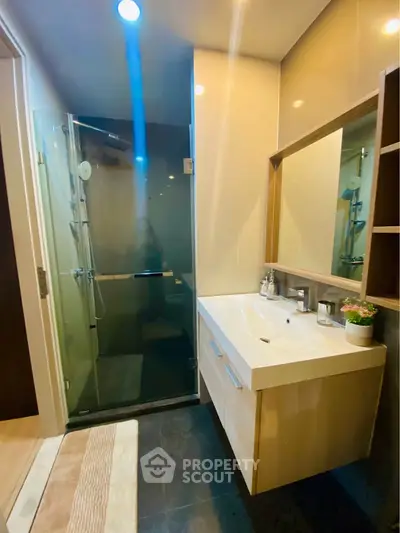 Modern bathroom with glass shower and sleek vanity in contemporary apartment.