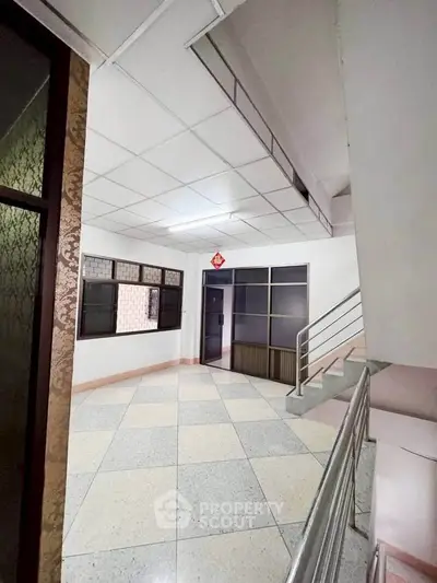 Spacious interior hallway with modern staircase and tiled flooring, ideal for residential or commercial use.