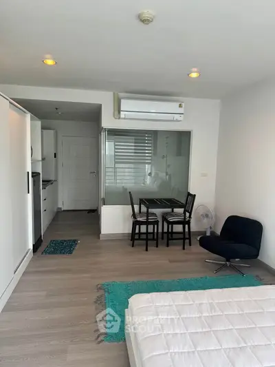 Modern studio apartment with open layout, featuring a cozy dining area and sleek air conditioning unit.