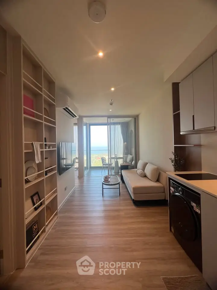 Modern living room with open layout and ocean view, featuring sleek furniture and built-in storage.