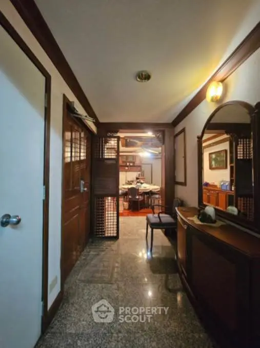 Charming hallway leading to a cozy living area with elegant wooden decor and warm lighting.