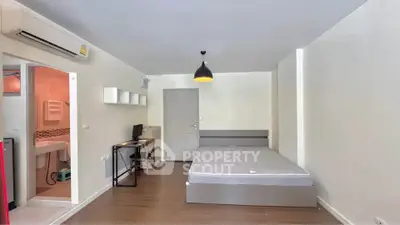 Modern studio apartment with minimalist design, featuring a cozy bed, compact workspace, and sleek bathroom.