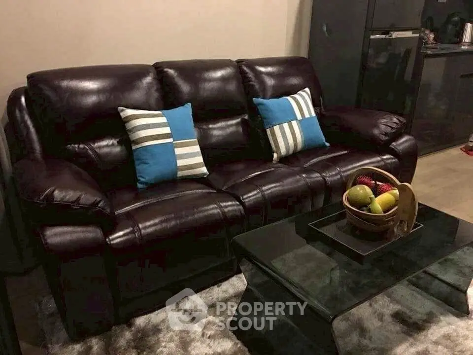 Stylish living room with dark leather sofa and modern glass coffee table, perfect for cozy evenings.
