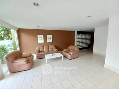 Spacious living room with leather sofas and natural light, perfect for relaxation.