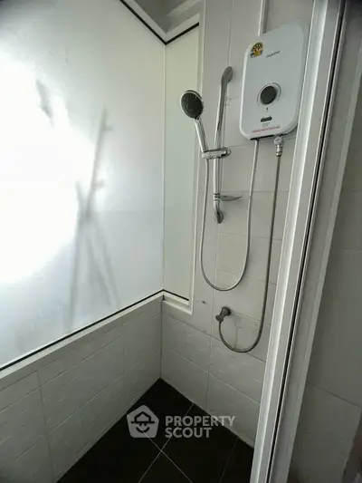 Modern bathroom with sleek shower and water heater, featuring minimalist design and bright lighting.