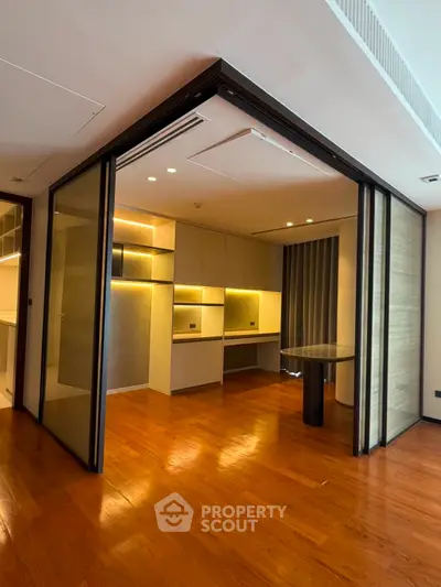 Modern interior with wooden flooring and sleek built-in cabinets, featuring ambient lighting and a stylish partition.